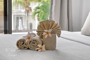 a towel and towels and flowers on a bed at The Jacuzzi Escape in Flic-en-Flac