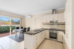 a kitchen with white cabinets and a dining room with a table at Leopold holiday home in Leopold