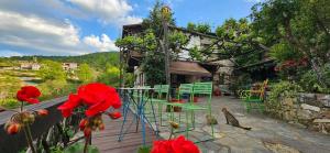 a patio with green chairs and red flowers in front of a building at Feggaropetra Inn Magic Mountain House in Palaios Panteleimonas