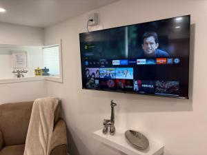 a bathroom with a flat screen tv on the wall at Silverado Suite Modern Quiet 2BR Queen's Downtown in Kingston