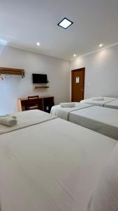 a room with three beds and a tv on the wall at Hotel e Restaurante Os Sertões in Canudos