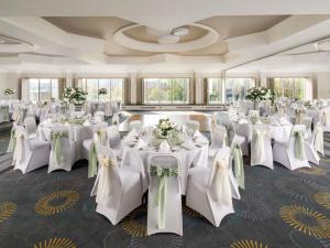 a banquet hall with white tables and chairs with flowers at Mercure Bedford Centre Hotel in Bedford