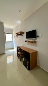 a living room with a table and a tv on the wall at Hotel e Restaurante Os Sertões in Canudos