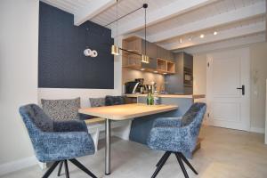 a kitchen with a wooden table and blue chairs at Alma & Eva, Whg 5 in Westerland