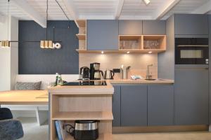 a kitchen with blue cabinets and a wooden table at Alma & Eva, Whg 5 in Westerland