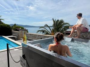 a woman sitting in a swimming pool next to a man at Design-Beachresort - with Pool - first line to the sea in Maslenica +44 photos