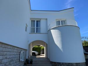 a white house with an archway and a lighthouse at Holiday Home Valica in Malinska