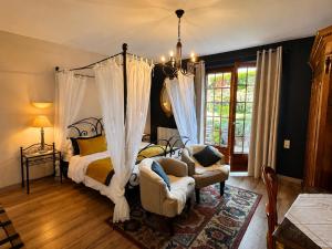 a bedroom with a canopy bed and a chair at Maison Kieffer - Hotel & Vins d'Alsace in Itterswiller