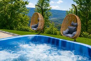 two wicker chairs sitting next to a swimming pool at Exclusive Villa Jacuzzi & BBQ in Şerbăneşti