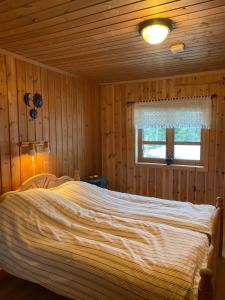 a bed in a wooden bedroom with a window at Toppastranda 20 in Sør-Fron