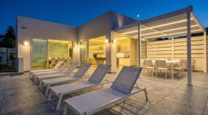 a row of chairs on a patio at night at Villa Ghea - Indoor Jacuzzi Pool, Sauna and Games Room in Mellieħa