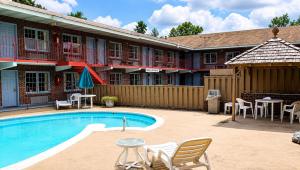 a pool in front of a hotel with chairs and a table at Captain John Smith Inn Williamsburg in Williamsburg
