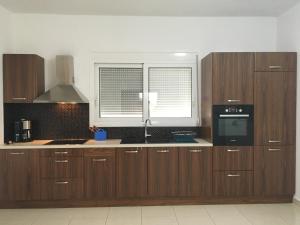 a kitchen with wooden cabinets and a window at Janis Home in Chrani