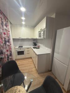 a kitchen with white cabinets and a white refrigerator at Urban Place by Kelvin in Narva