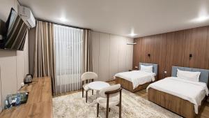 a hotel room with two beds and a table and chairs at Turon plaza hotel in Bukhara