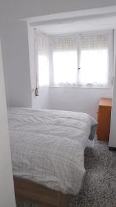 a white bedroom with a bed and two windows at Playa a dos pasos in Santa Pola