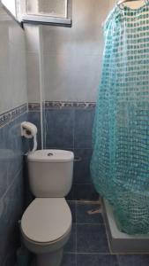 a bathroom with a toilet and a blue shower curtain at Playa a dos pasos in Santa Pola