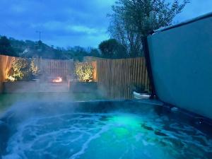 a hot tub in a backyard at night at Hydrangea House in Hythe