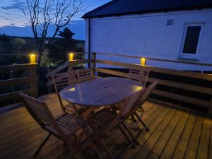 a wooden table and chairs on a deck at night at Beautiful 2-Bed semi rural cottage enclosed garden in Drummore