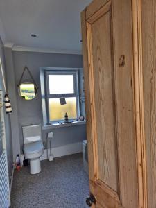 a bathroom with a toilet and a window at Beautiful 2-Bed semi rural cottage enclosed garden in Drummore +30 photos