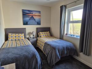 a bedroom with two beds and a window at Beautiful 2-Bed semi rural cottage enclosed garden in Drummore