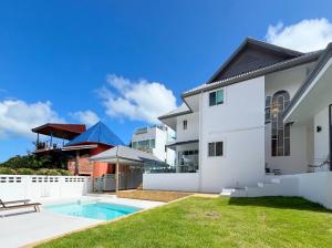 a white house with a swimming pool in a yard at Villa Tara - Sea view 5Br Rawai in Ban Saiyuan (1)