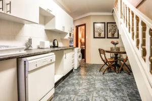 a kitchen with white cabinets and a table and a staircase at Avemore Island Apartment Sedgefield in Sedgefield