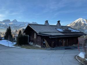 a house on the side of a road with mountains at Le vieux chalet in La Forclaz +1 photo