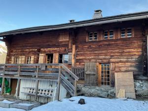 an old wooden house with a porch in the snow at Le vieux chalet in La Forclaz