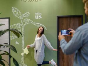 a man taking a picture of a woman in front of a wall at Ibis Styles Aschaffenburg in Aschaffenburg