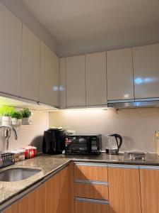 a kitchen with white cabinets and a sink and a microwave at Ocean View Escape at The Mactan Newtown in Punta Engaño