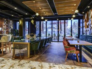 a restaurant with chairs and tables and a bar at Mercure Timisoara in Timişoara