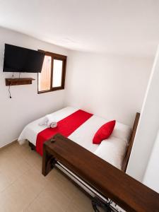 a bedroom with a bed with red pillows and a television at KOKOA GARDEN INN in San Vicente de Chucurí +3 photos