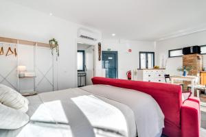 a bedroom with a red couch and a kitchen at Studio - Old Town Albufeira in Albufeira
