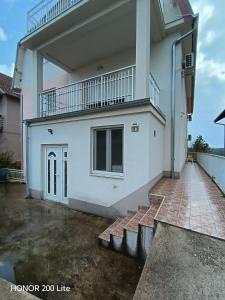 a white house with a balcony and a patio at Komforna Soba U Centru #3 in Mladenovac