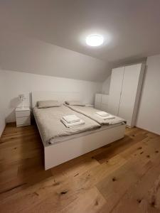 a white bedroom with a bed and a wooden floor at Hiša Čebron in Podnart