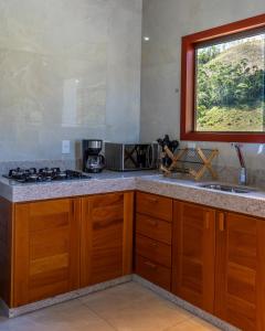 a kitchen with wooden cabinets and a sink and a window at Chalé Estalagem Sítio Sossego in Domingos Martins +3 photos