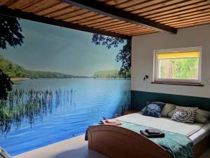 a bedroom with a large window overlooking a lake at Mazurski Kubryk in Ruciane-Nida