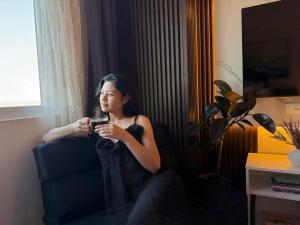 a woman sitting in a chair holding a cell phone at Maison Angela Suites in Biñan