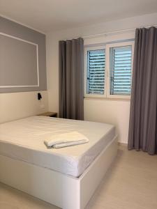 a white bedroom with a large white bed and two windows at Apartmani Tepli Bok in Primošten +81 photos