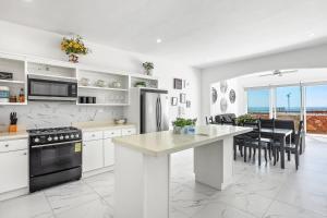 a kitchen with white cabinets and a black appliance at Dog-Friendly Home with Heated Pool, Hot Tub, Partial Ocean Views & Balcony in Rosarito