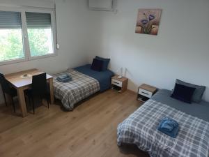 a room with two beds and a desk and a table at Soba Za Odmor # in Mladenovac