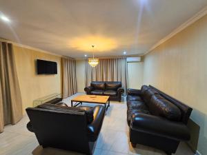 a living room with leather furniture and a tv at Posimuma in Centurion