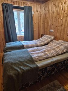 two beds in a room with wooden walls and a window at Sjøhaug Rorbu, Fishcermanns cabin in Moskenes