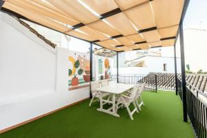 a table and chairs on a balcony with green flooring at Hospedería Boho Granada by eme hoteles in La Zubia