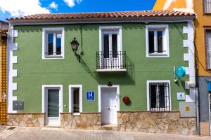 a green building with a white door and balcony at Hospedería Boho Granada by eme hoteles in La Zubia