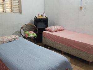 a bedroom with two beds and a chair and a dresser at Pousada Mais E Vida 24h in Teresina