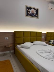a bed with a yellow headboard in a room at AA Boutique Hotel in Shkodër