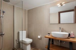 a bathroom with a sink and a toilet and a mirror at Utopia Suites in Egina