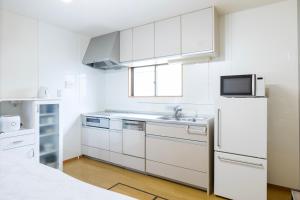 a white kitchen with a sink and a refrigerator at gently stay Nagoya in Nagoya
